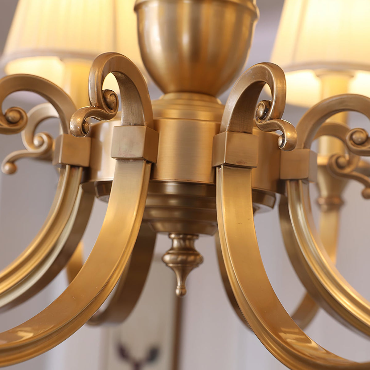 Close view of the brass scroll details and arm fixings around the centre of this Clérachic chandelier.