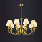 This Clérachic brass chandelier with eight pleated shades hangs on a chain against a dark charcoal backdrop.