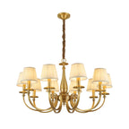 Clérachic brass chandelier with a wide arm spread and pleated white shades, on a white backdrop with a wrapped chain.