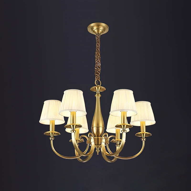 Clérachic brass chandelier with six pleated shades on a dark charcoal backdrop, hung from a brass ceiling plate and chain.