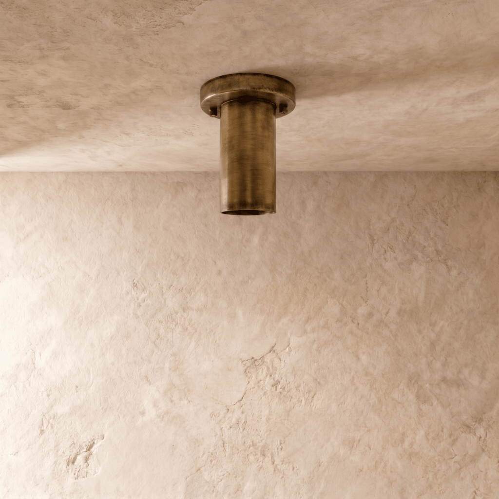 This vintage brass Clérachic ceiling light is shown from below, its round lens glowing softly.