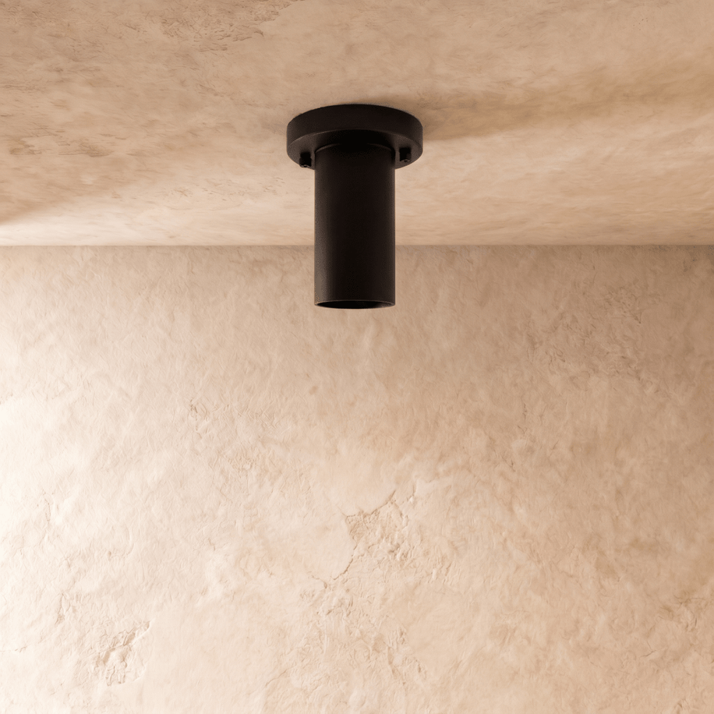 This black Clérachic ceiling light is shown from directly below, its round lens glowing warmly.