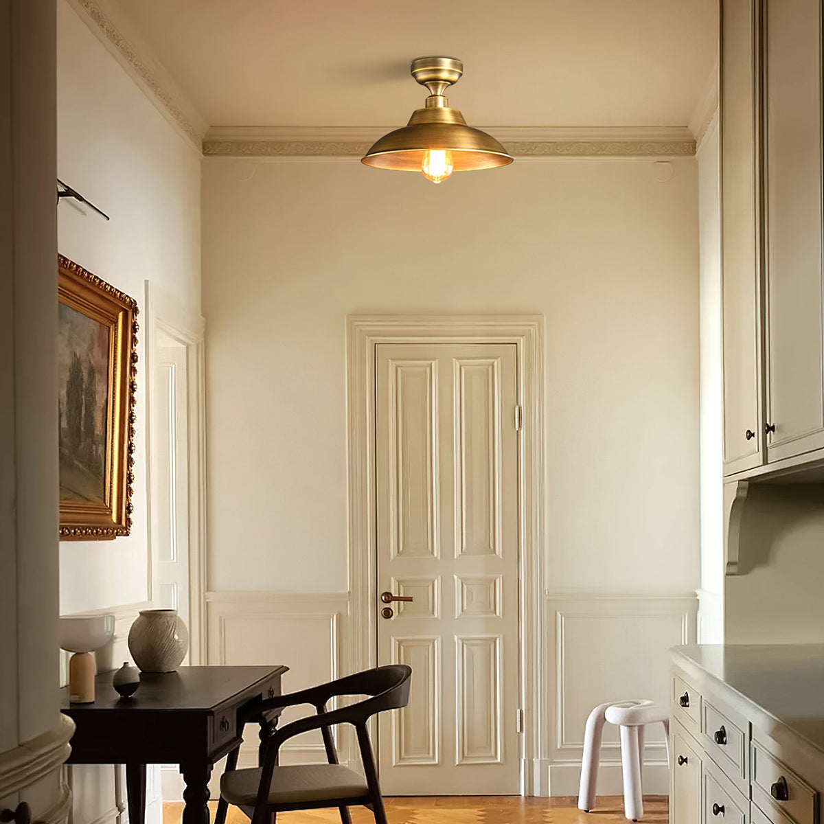 On a cream ceiling above a panelled door and a dark desk with a black chair, a Clérachic brass dome ceiling light stays unlit.
