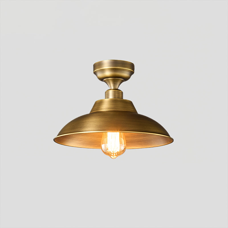 This Clérachic ceiling light in Antique Brass on a pale grey backdrop, a wide shallow dome under a stepped round canopy with a warm bulb.