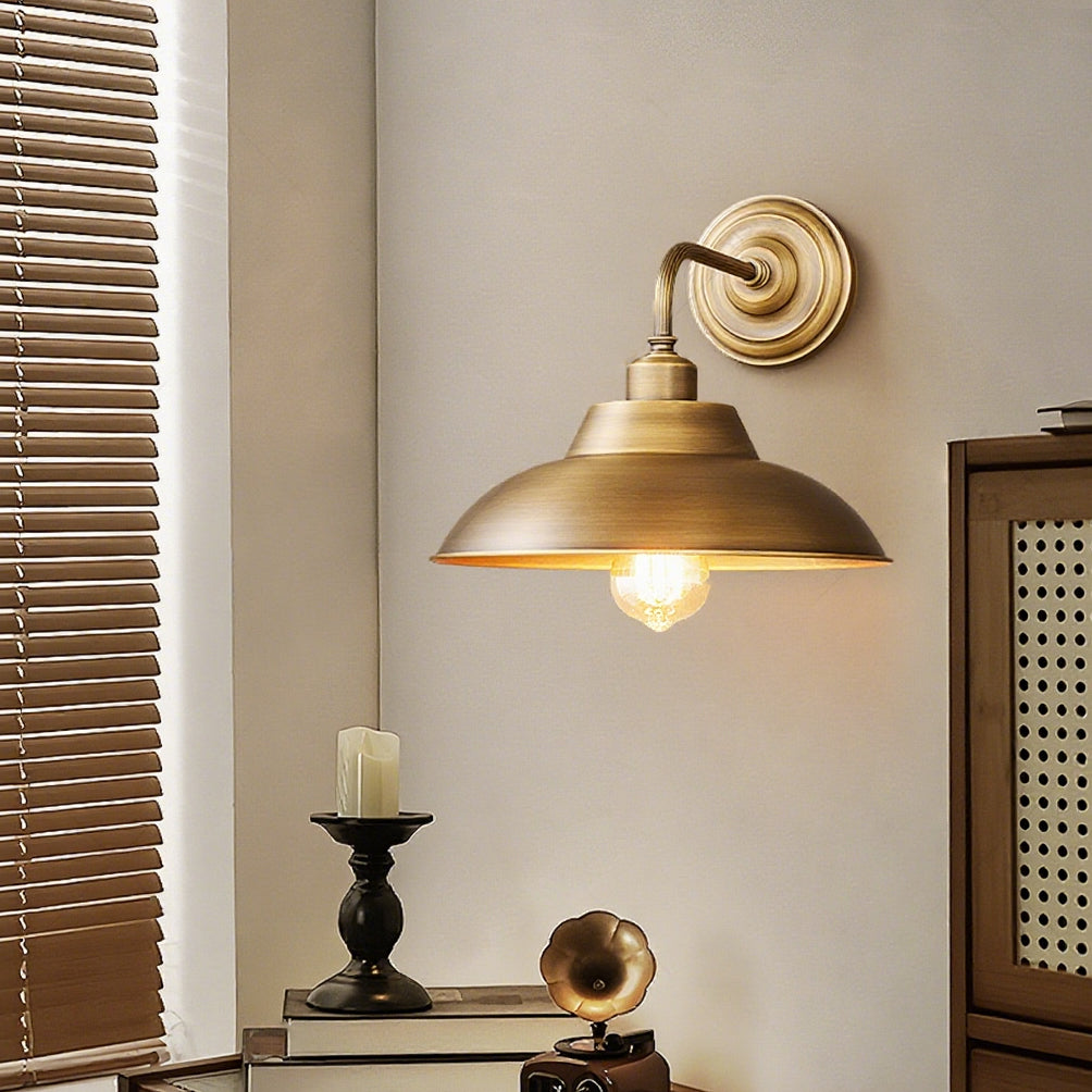Close to a window blind, this Clérachic brass wall light glows over a console with a candle and a vintage horn gramophone.