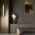 The Clérachic Brass-Edged Shield Wall Sconce lit on a bronze hallway panel, its stone glowing beside a sculptural table lamp.