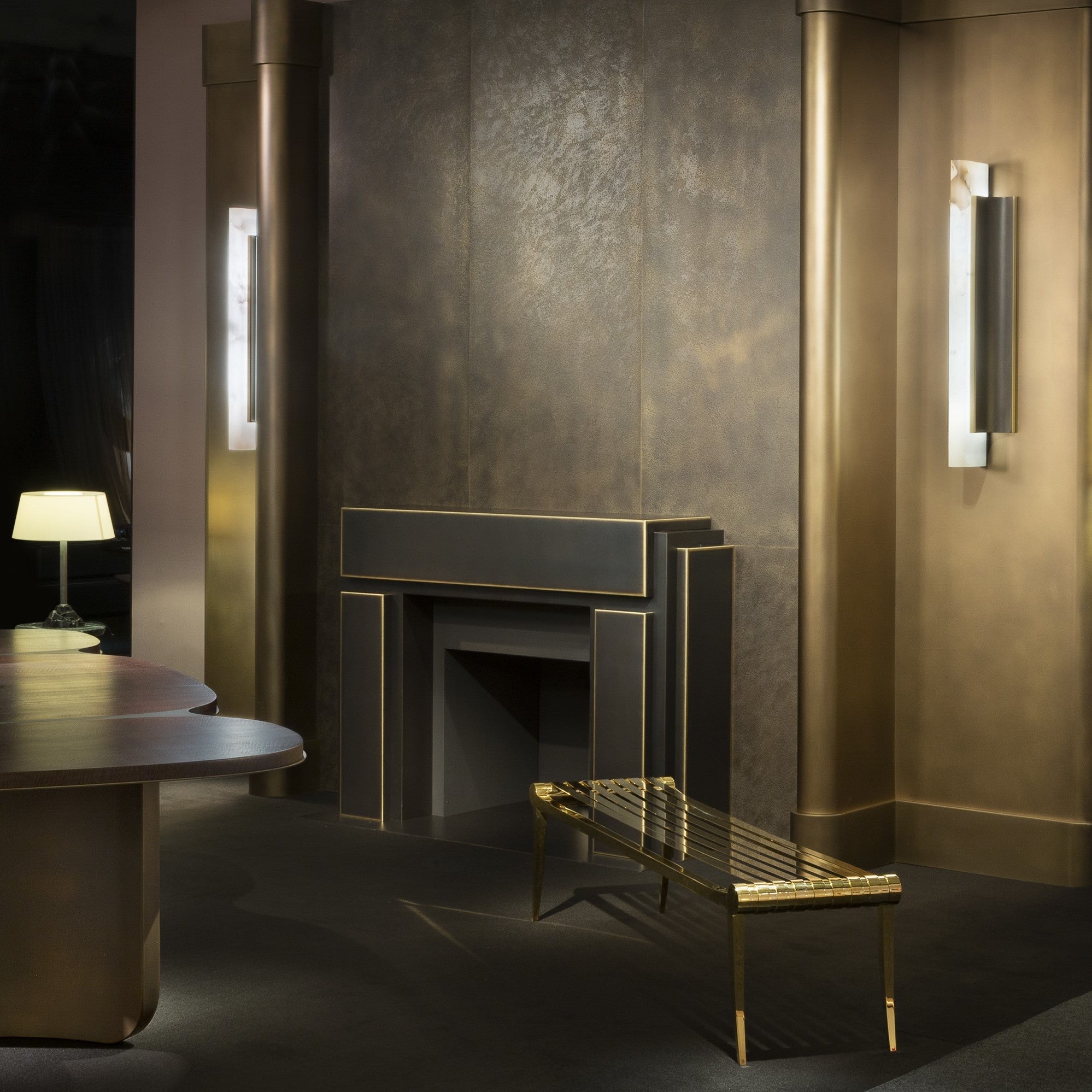 Two Clérachic Brass-Edged Shield Wall Sconces lighting a dark panelled room, one on each column flanking the fireplace.