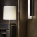 Close view of a lit Clérachic Brass-Edged Shield Wall Sconce, warm light leaving through the stone and off the curved bronze shield.
