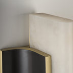 Detail of the Clérachic Brass-Edged Shield Wall Sconce where the alabaster bar overruns the shield, a shadow gap holding stone off metal.