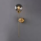 Full-length view of the Clérachic Brass-Finish Globe Wall Sconce, the brass tail dropping well below the fixing point on a grey wall.