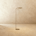 Clérachic floor lamp in vintage brass with a leaf-shaped shade tilted upward on a slender curved rod.