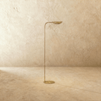 This polished brass Clérachic floor lamp is shown from a different angle, the leaf shade tilted upward.