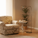 This vintage brass Clérachic floor lamp lights a floral armchair beside a round table set with books.