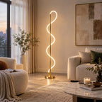 Warm light from the looping silicone strip of this Clérachic floor lamp falls on a cream armchair and a marble coffee table.