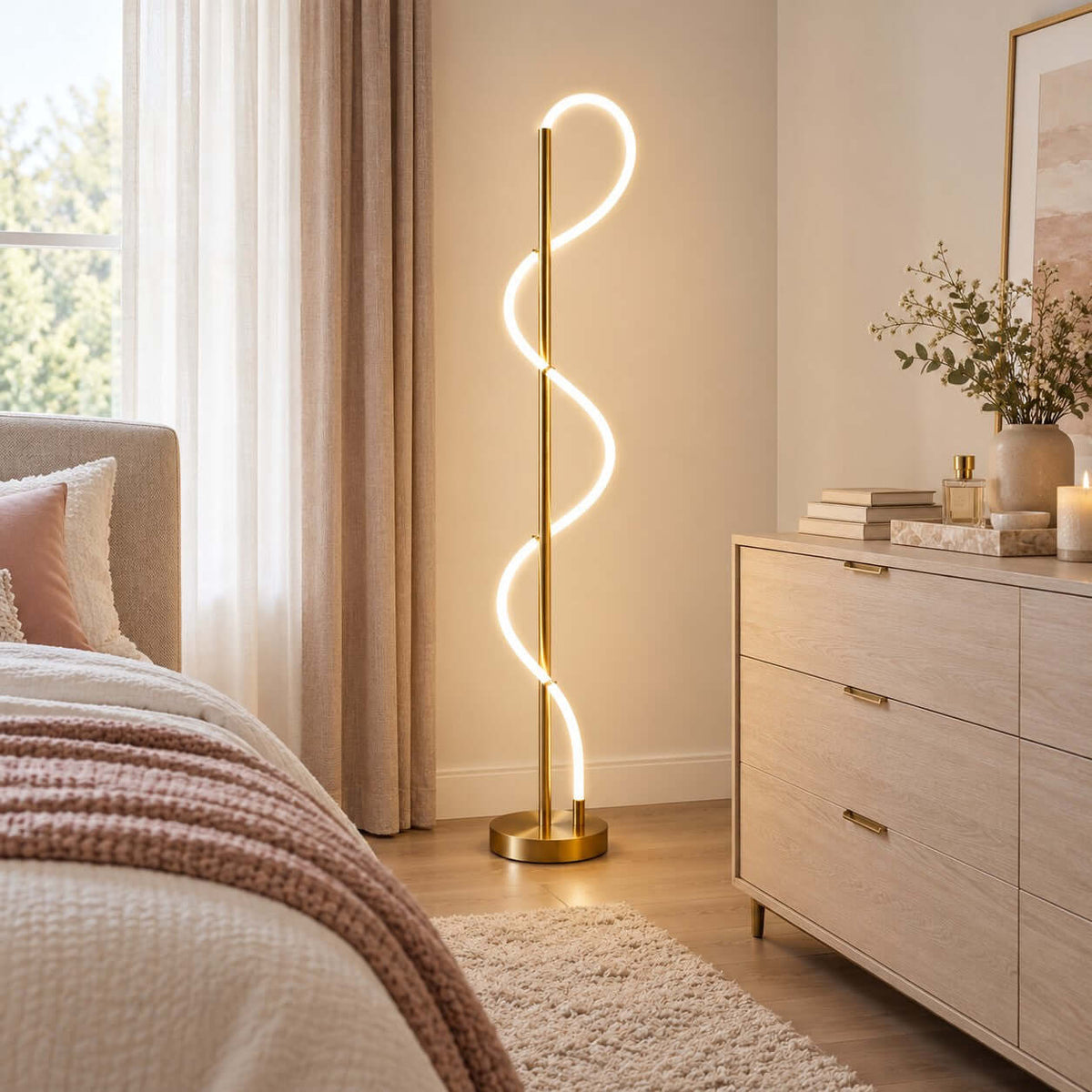 A pale wood chest of drawers and a rose-pink bed throw sit beside this lit Clérachic floor lamp, which glows against a warm wall.