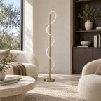 Switched off, this Clérachic floor lamp stands in front of a dark wood bookcase and a boucle sofa, its white silicone curve visible.