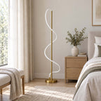 Unlit in a bedroom with a pale wood nightstand and a throw on a bench, this Clérachic floor lamp shows its soft white silicone coil.
