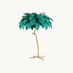 Teal ostrich-feather canopy on a slender gold branch-style stem, this Clérachic floor lamp shown on a plain white backdrop.