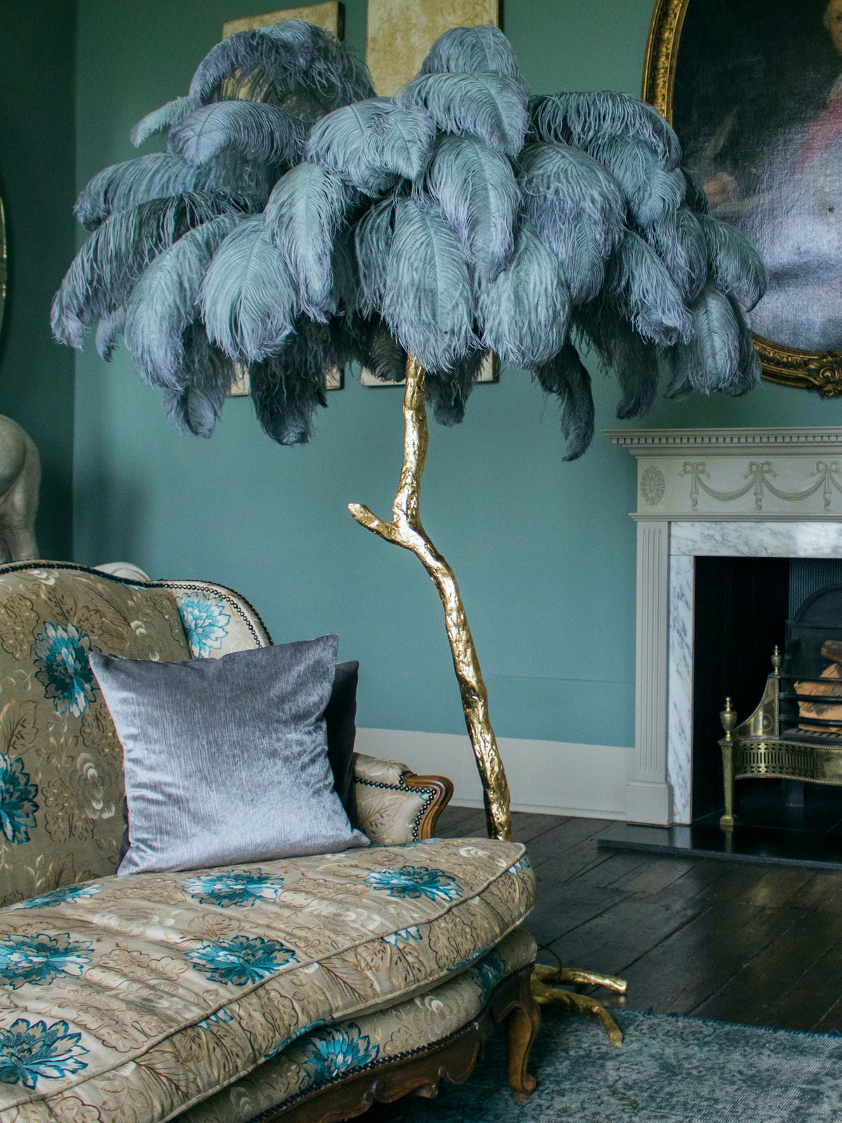 Smoky blue-grey plumes on a Clérachic floor lamp in a teal-walled room, by a patterned sofa and a marble fireplace.