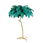 Teal feathers on a Clérachic floor lamp, photographed whole on white, with the gold stem and its claw-like base fully visible.