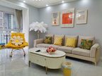 A small white-feathered Clérachic floor lamp in the corner of a grey living room, with a yellow chair and a cream sofa.
