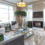 Dark green plumes on a Clérachic floor lamp in a grey living room with a glass coffee table, fireplace and wall-mounted television.