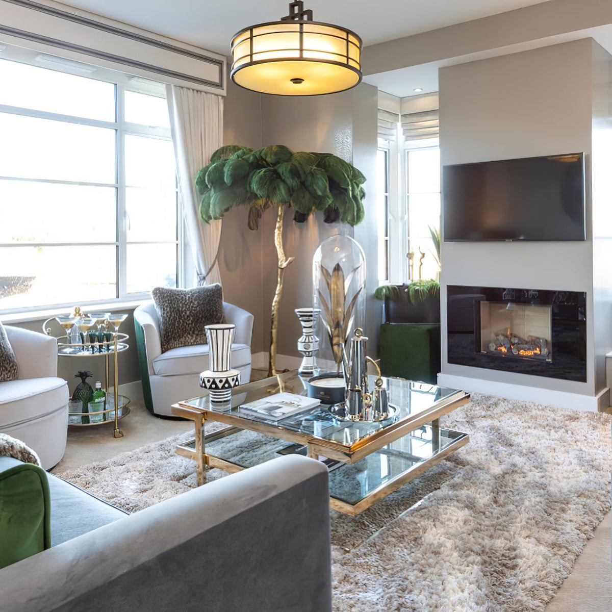 Dark green plumes on a Clérachic floor lamp in a grey living room with a glass coffee table, fireplace and wall-mounted television.