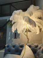 Lit white plumes on a Clérachic floor lamp, glowing over a blue tufted sofa in a loft with a steel staircase.