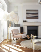 Cream-white plumes on a Clérachic floor lamp in a bright room with a fireplace, a pink armchair and a shaggy rug.
