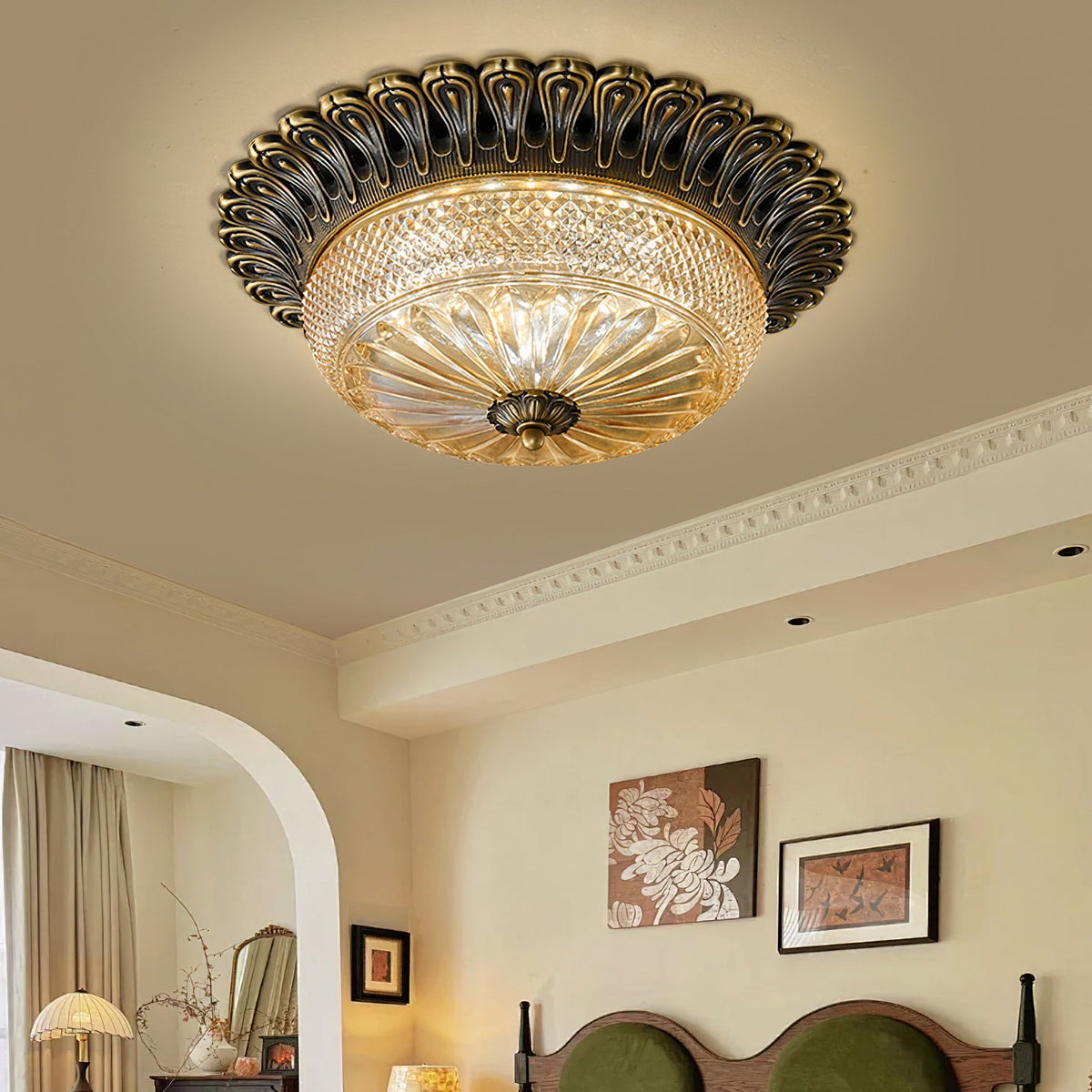 Looking up at this Clérachic ceiling light, its carved dark brass rim and cut amber glass bowl lit against a cream ceiling with cornice.