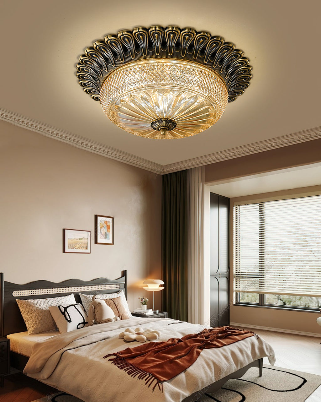 A Clérachic ceiling light above a bed with a rust-red throw and cushions, with a window and bedside lamp in the soft evening light.