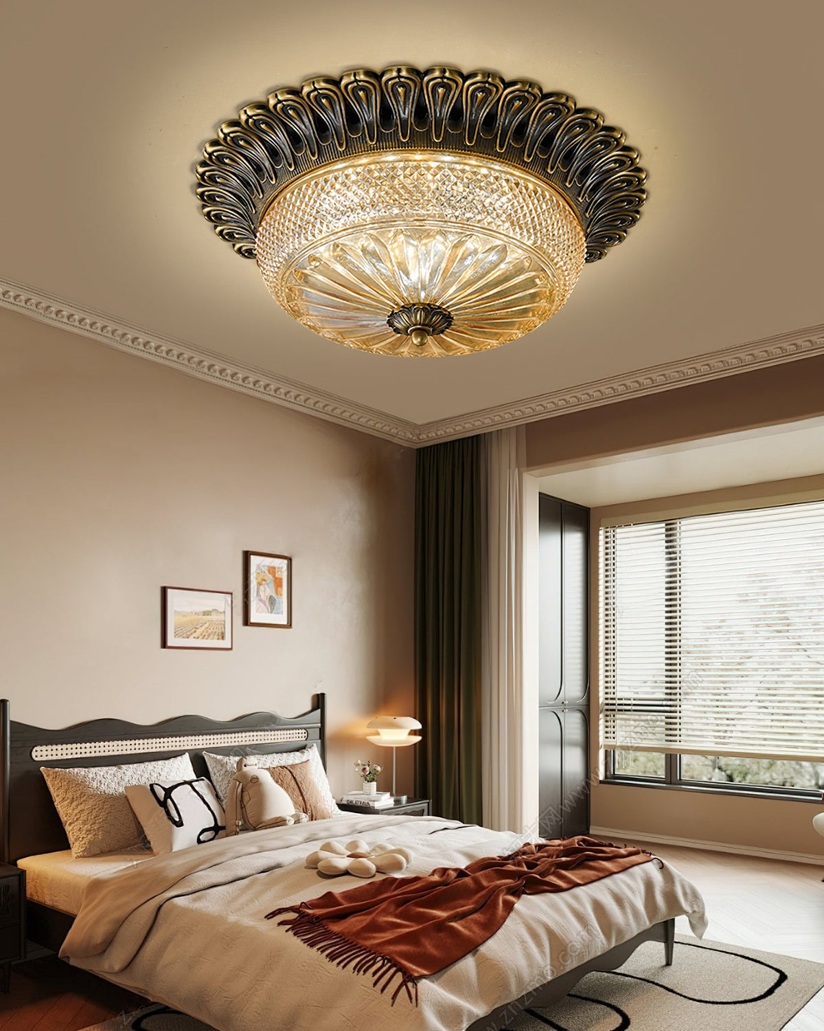 A Clérachic ceiling light above a bed with a rust-red throw and cushions, with a window and bedside lamp in the soft evening light.