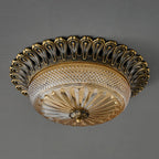 Underside view of this Clérachic ceiling light on grey, showing the ribbed amber glass and the brass finial at the centre.