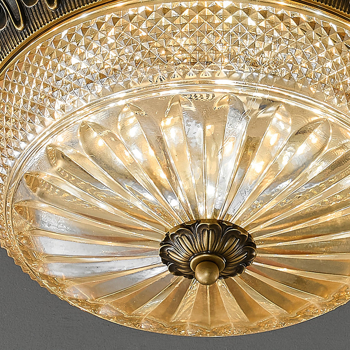 Close view of the ribbed amber glass and textured diamond-cut band on this Clérachic ceiling light, with the brass finial at its centre.