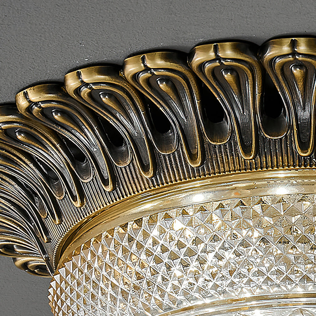 Close view of the carved, teardrop-pierced antique brass rim on this Clérachic ceiling light, above the diamond-cut glass band.