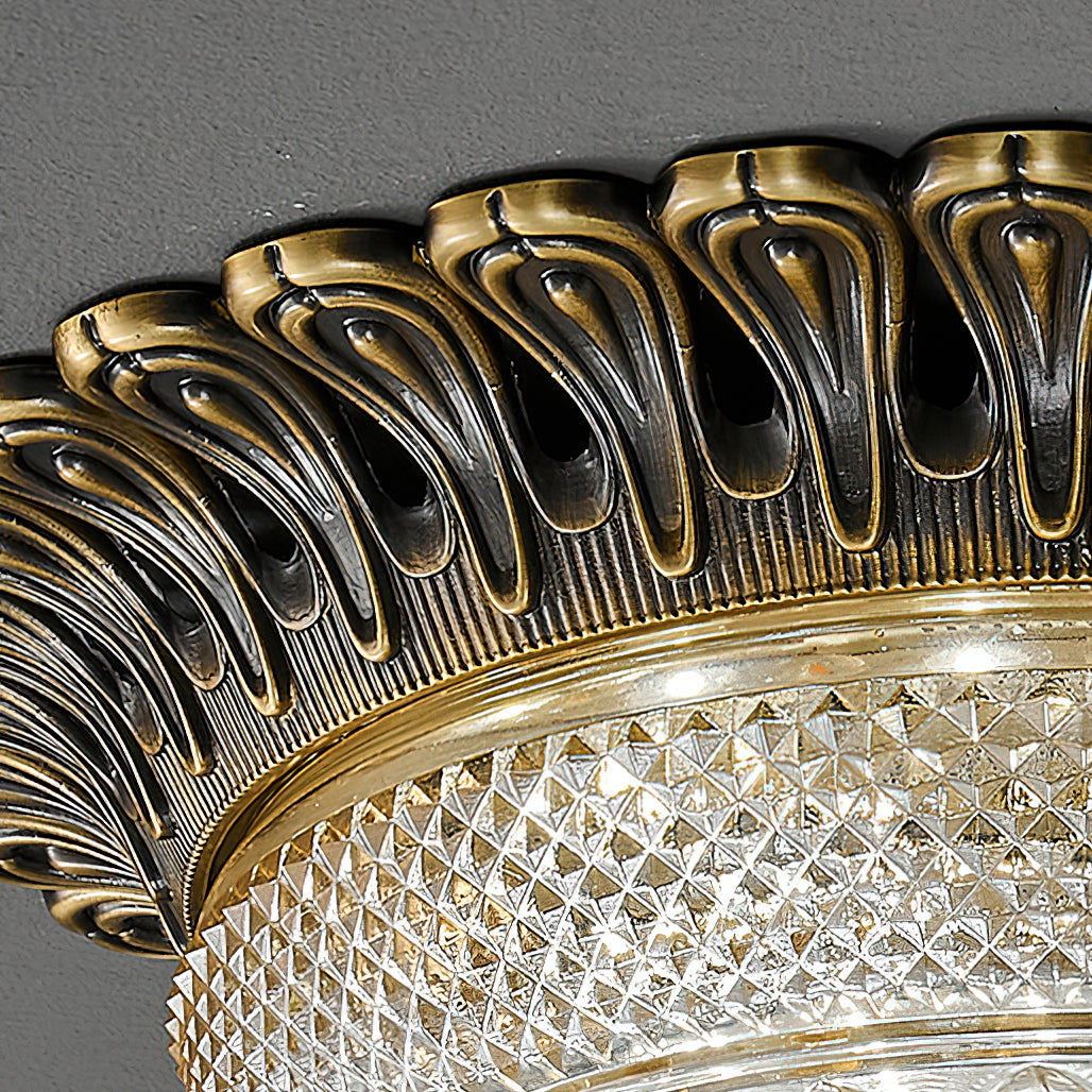 Close view of the carved, teardrop-pierced antique brass rim on this Clérachic ceiling light, above the diamond-cut glass band.