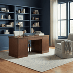 A Clérachic table lamp on a wooden desk in front of blue bookshelves, with an armchair and a blanket to the right.