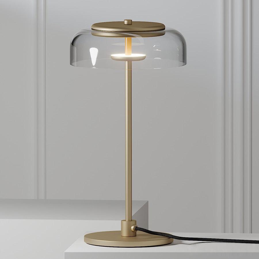 Close view of the clear glass dome and brass-toned cap on a Clérachic table lamp, with its stem and round base on a pale surface.