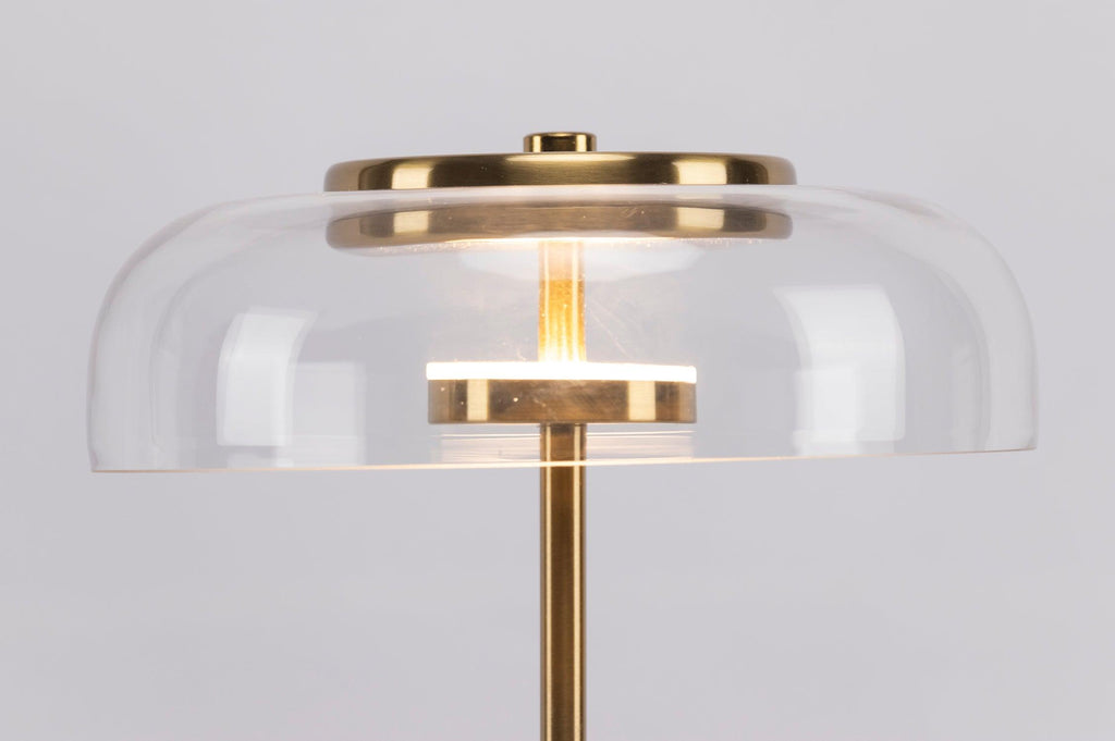 Close view of the clear glass dome with its brass cap and a lit LED ring on this Clérachic table lamp.