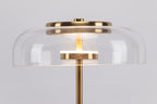 Close view of the clear glass dome with its brass cap and a lit LED ring on this Clérachic table lamp.