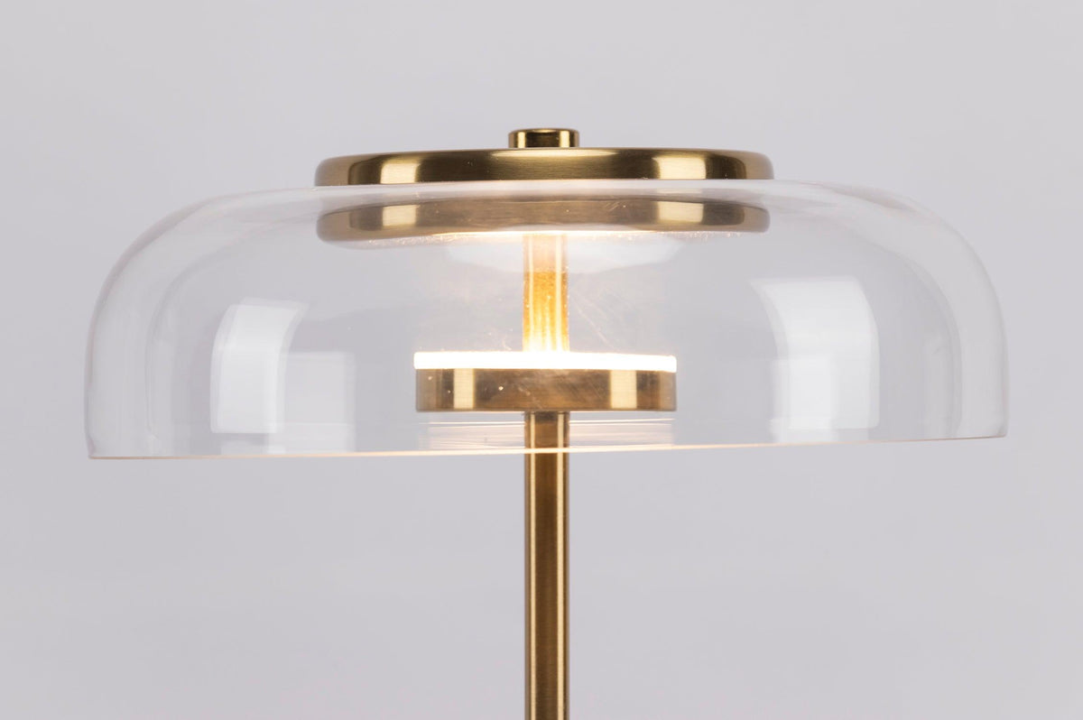 Close view of the clear glass dome with its brass cap and a lit LED ring on this Clérachic table lamp.