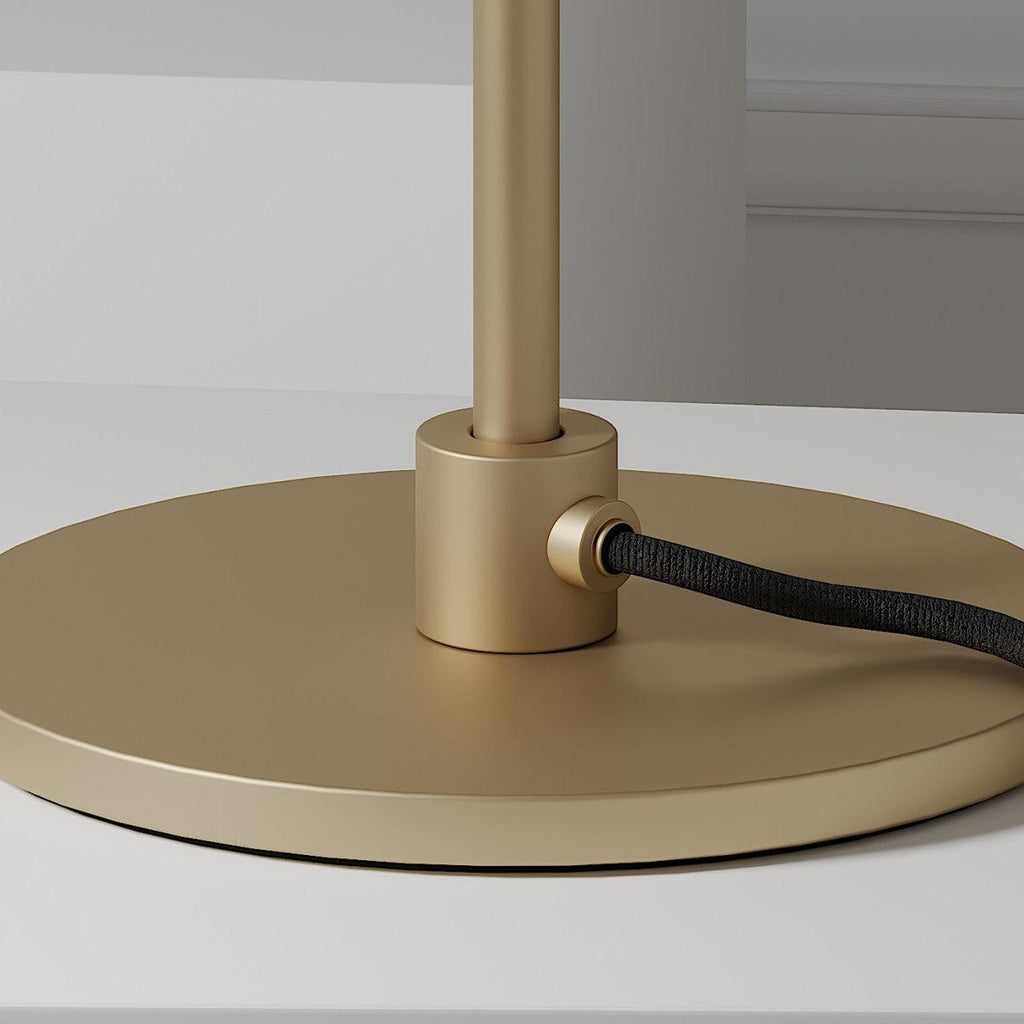 Close view of the brass collar, the cable inlet and the round matt-gold base of this Clérachic table lamp.