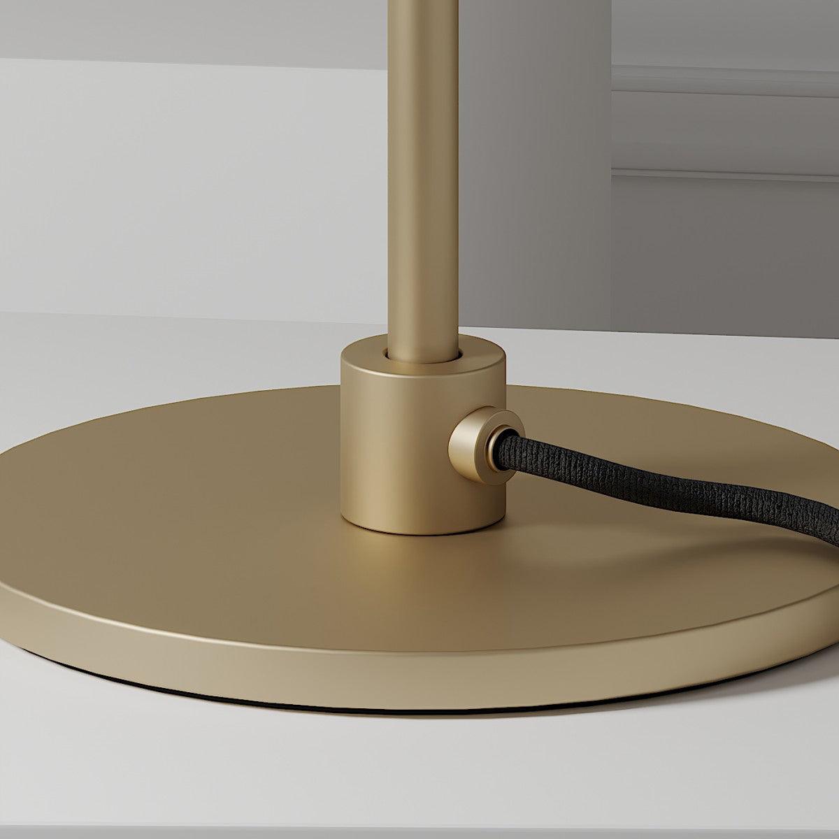 Close view of the brass collar, the cable inlet and the round matt-gold base of this Clérachic table lamp.
