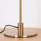 Close view of the brass collar and the round base of this Clérachic table lamp, with the cord entering on the left.