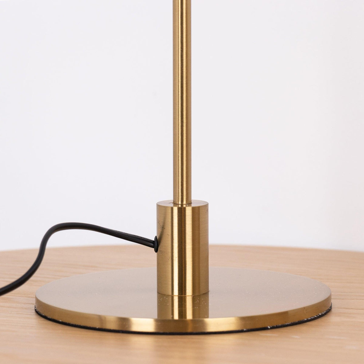 Close view of the brass collar and the round base of this Clérachic table lamp, with the cord entering on the left.