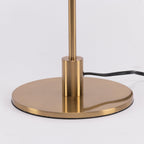 Close view of the brass base, the collar and the black cord on this Clérachic table lamp, with a shiny finish.