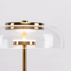 Close, lit view of the glass dome and the glowing LED disc inside this Clérachic table lamp, with its brass cap above.