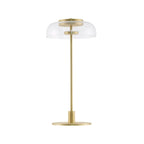 A Clérachic table lamp with a clear glass dome, shown unlit on a white background, standing on a slim brass stem and a flat round base.