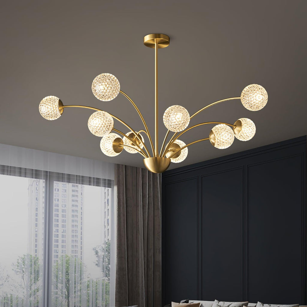 A Clérachic brass chandelier with textured globes glowing warmly above a dark panelled room, with a tall window and grey curtains beside it.