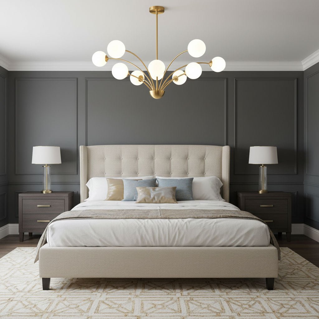 A Clérachic brass chandelier with white glass globes over a bed with a cream tufted headboard, in a charcoal panelled bedroom.